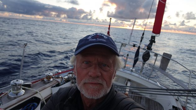 A man wearing a cap on the deck of a boat in the middle of the ocean