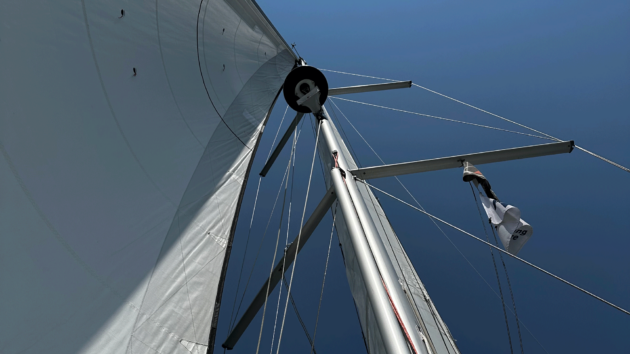 The mast with main sail and blue sky behind