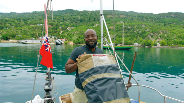 Necksonne, local bar and hostel owner on Île de la Tortue, takes delivery of the sail.